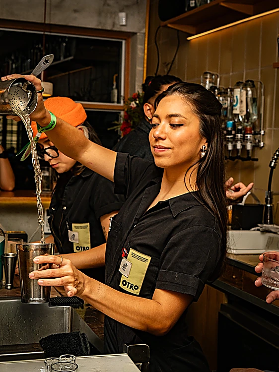 Bartender invitada de Otro Bar sirve con una cuchara de bar en la contrabarra