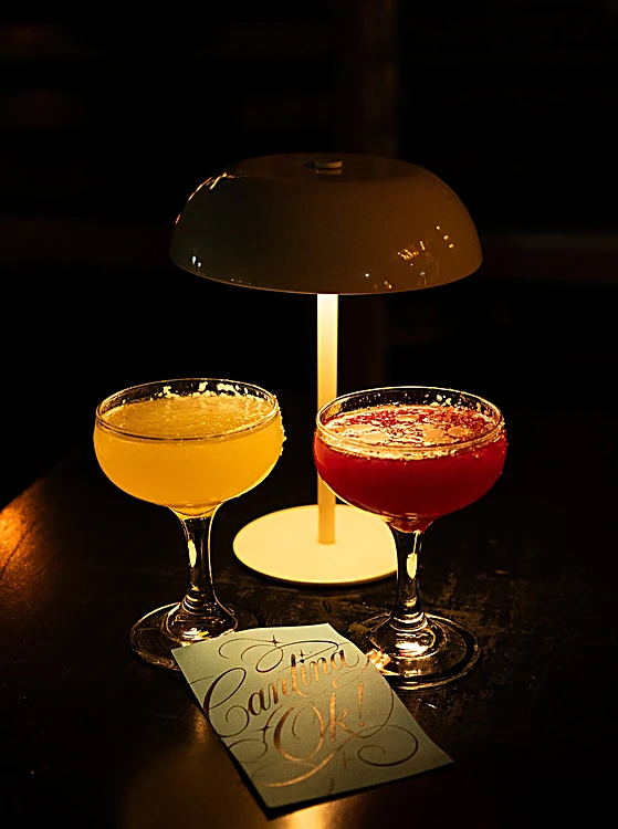 Dos margaritas, una amarilla y una roja, bajo una lámpara de mesa en la penumbra
