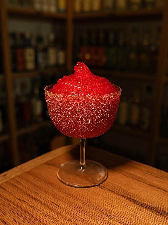 Margarita de Jamaica frozen, roja intensa, en copa escarchada sobre la barra de roble